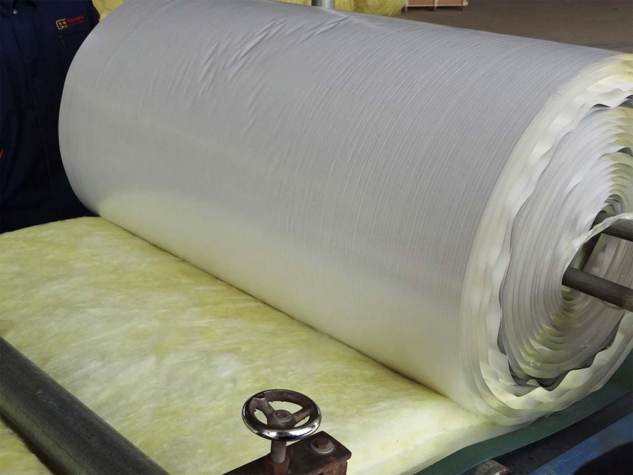 Large roll of vinyl-faced fiberglass insulation coming off the production line
