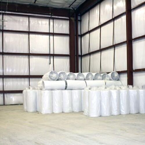 Vinyl-faced fiberglass insulation rolls stacked and wrapped — the standard facing that dominates U.S. metal-building jobs