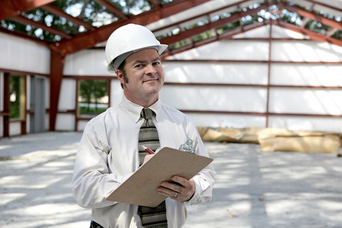 White vinyl-faced fiberglass insulation rolls stacked inside an insulated metal building — the actual material Insulation Overstock ships